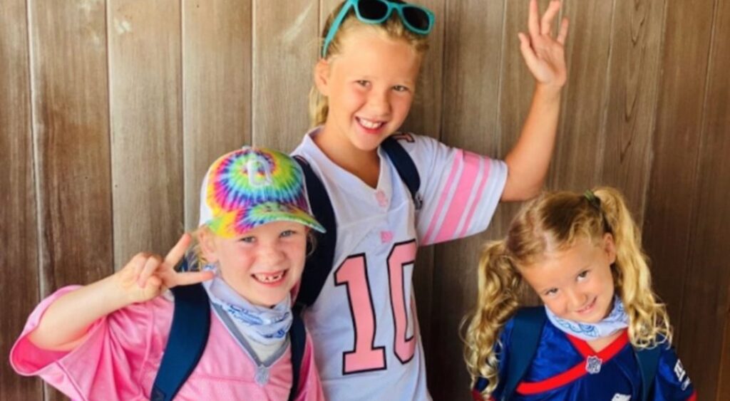 A photo of Eli Manning's three daughters smiling for the camera and waving.