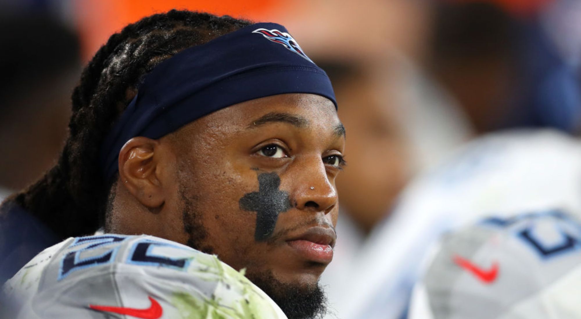 Derrick Henry with braids and a headband in a football uniform with a black cross on his cheek.