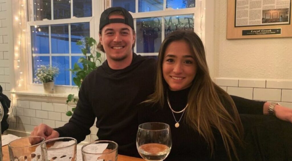 Kenny Pickett and girlfriend Amy Paternoster smiling at a restaurant, both wearing black.