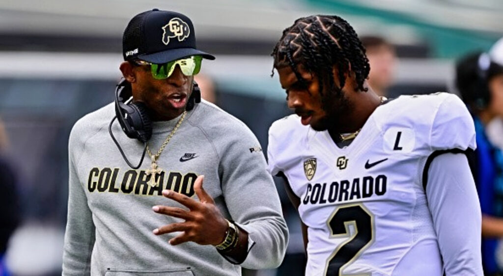 Deion Sanders speaking to son Shedeur Sanders on sidelines.