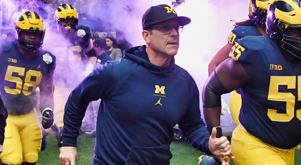 Jim Harbaugh runs onto the field with his players.