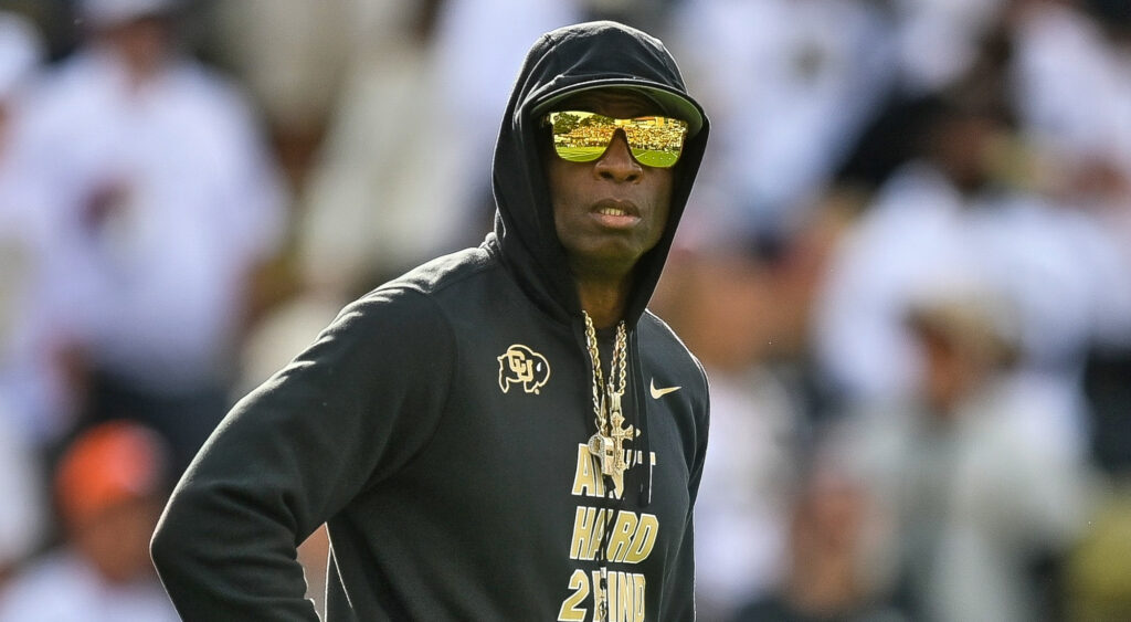 Deion Sanders in sweater, jewlery, and sunglasses