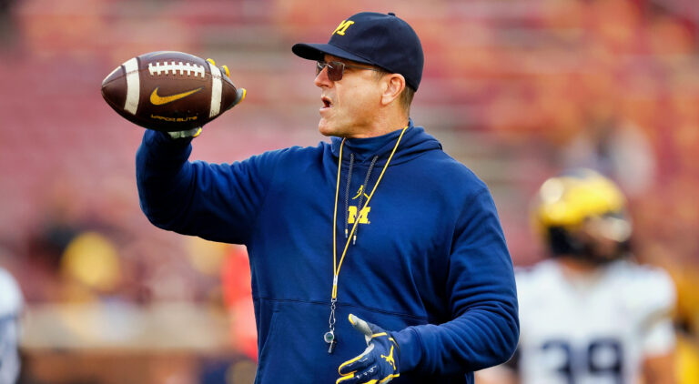 Jim harbaugh holding a football