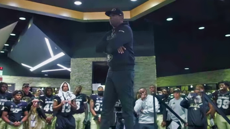 Deion Sanders speaking to Colorado Buffaloes players in locker room.