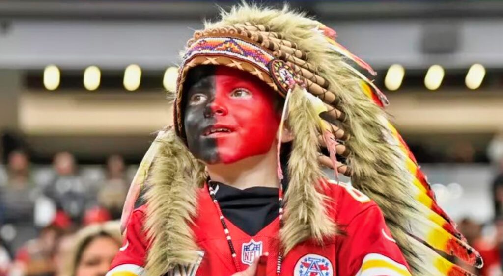 Chiefs fan with his face painted wearing headdress.