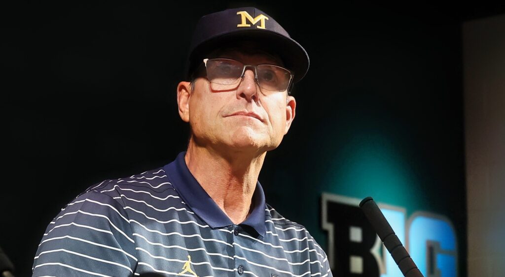 Michigan head coach Jim Harbaugh looking on while talking to media.