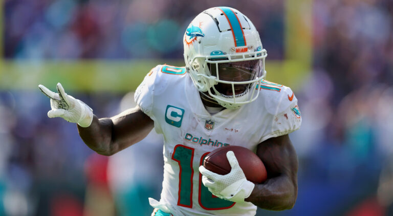 Tyreek Hill holding two fingers up while running with football