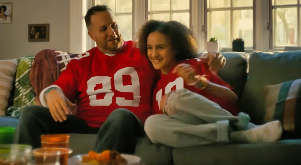 Dad holding daughter on couch in commercial