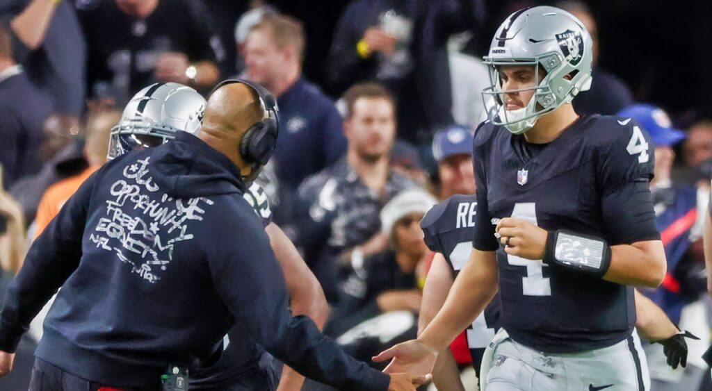 Las Vegas Raiders QB Aiden O'Connell slaps Antonio Pierce's hand as he runs off the field.