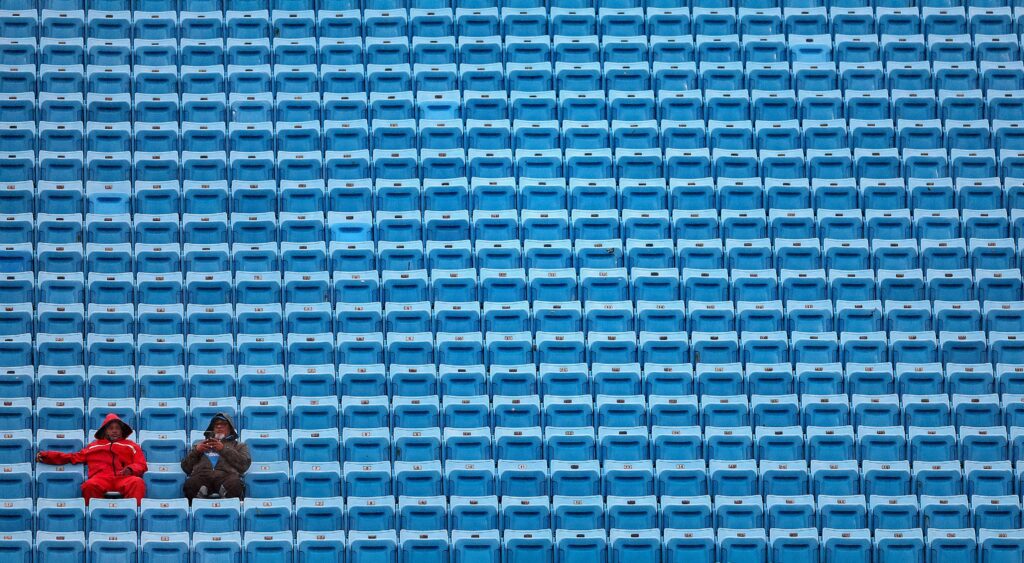 Two fans sit among a bunch of empty seats at a Carolina Panthers game.