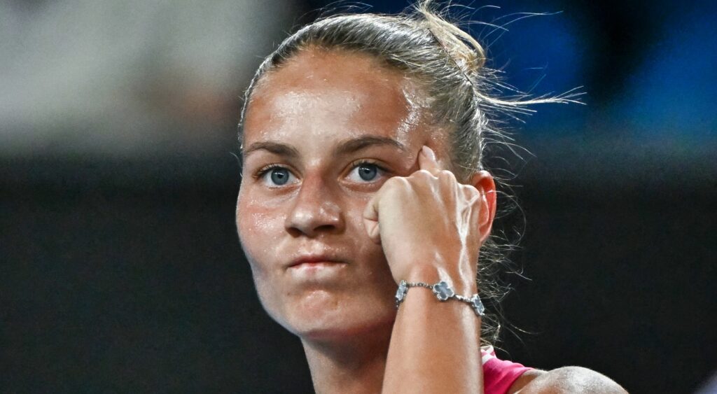 Marta Kostyuk points to her head during a tennis match.