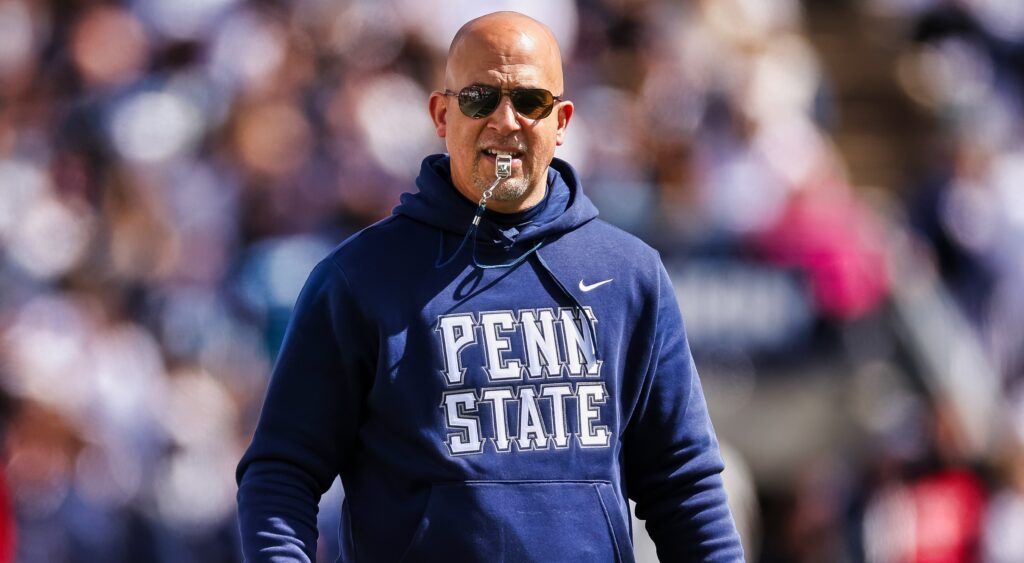 Penn State head coach James Franklin looks on with a whistle in his mouth.