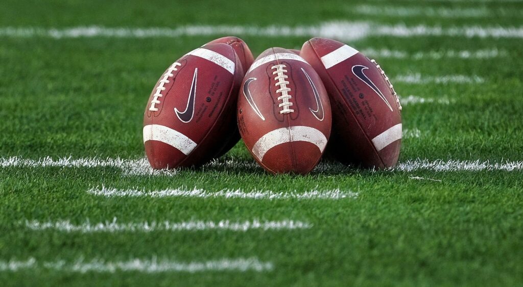 Three College footballs on field