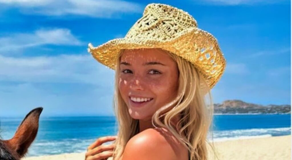 Olivia Dunne poses on the beach with a horse.