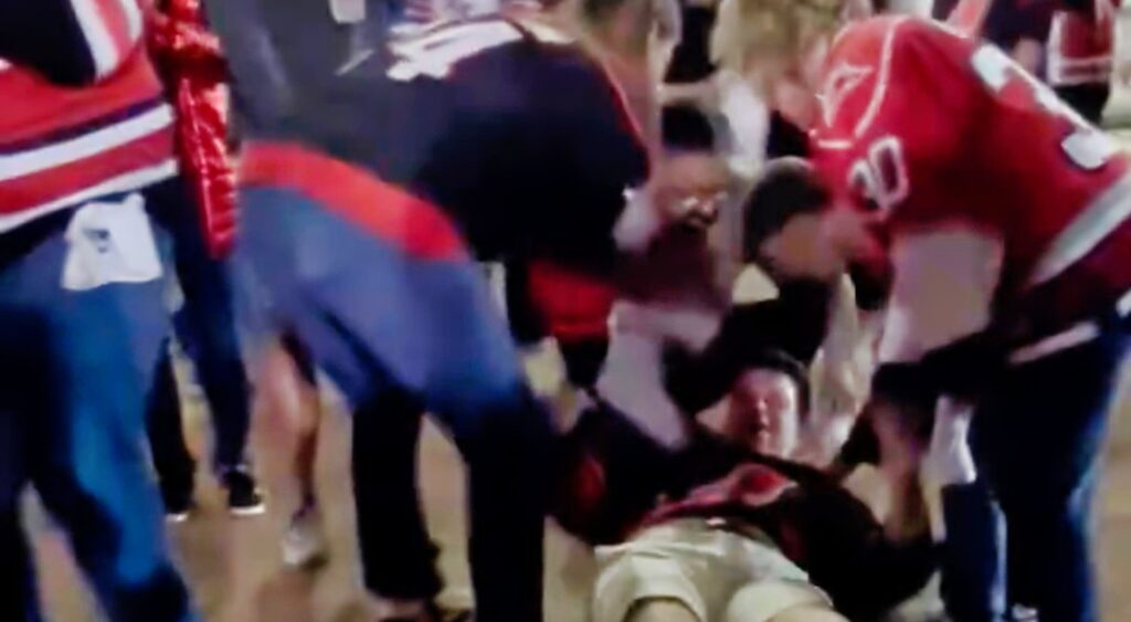 Carolina Hurricanes fan on the ground being attended to by other fans after getting knocked out.