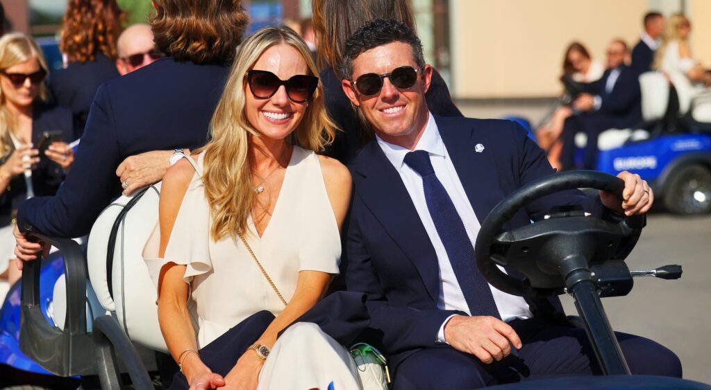 Rory McIlRoy and Erica Stoll smiling in golf cart.