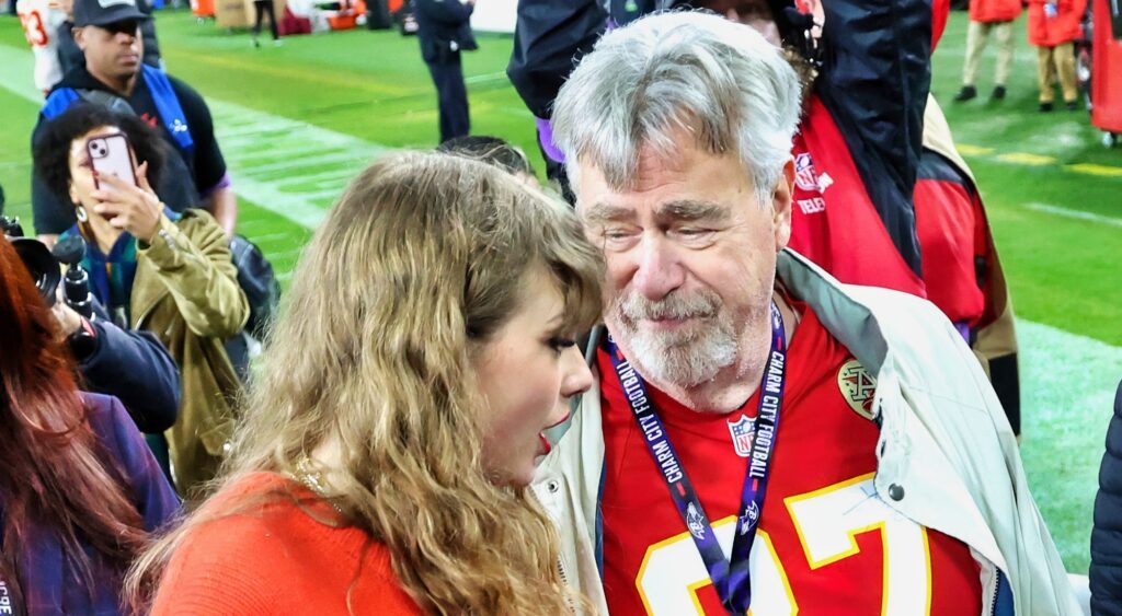 Travis Kelce's dad and Taylor Swift on the field after a game.