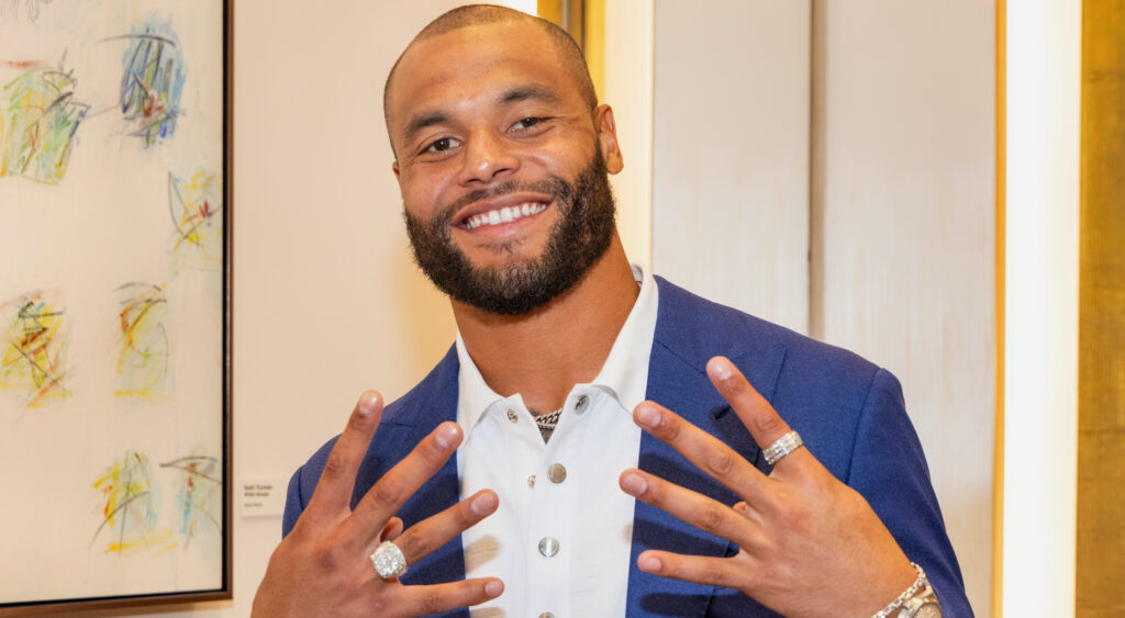 Dak Prescott poses for the camera with his fingers raised.