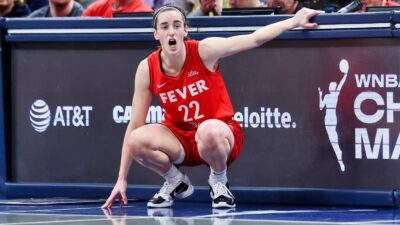 Caitlin Clark kneeling down on sidelines