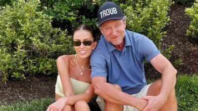 Wayne Gretzky and Paulina posing while seated on grass