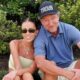 Wayne Gretzky and Paulina posing while seated on grass