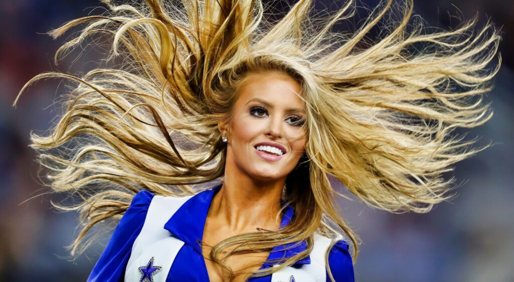 Dallas Cowboys cheerleader with her hair waving in the air.
