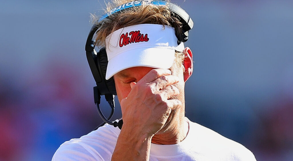 Lane Kiffin with a hand over his face