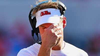 Lane Kiffin with a hand over his face