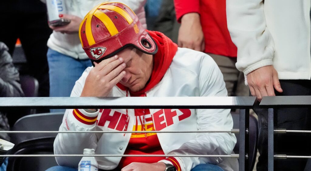 Kansas City Chiefs NFL Fan sits with hand on his head.