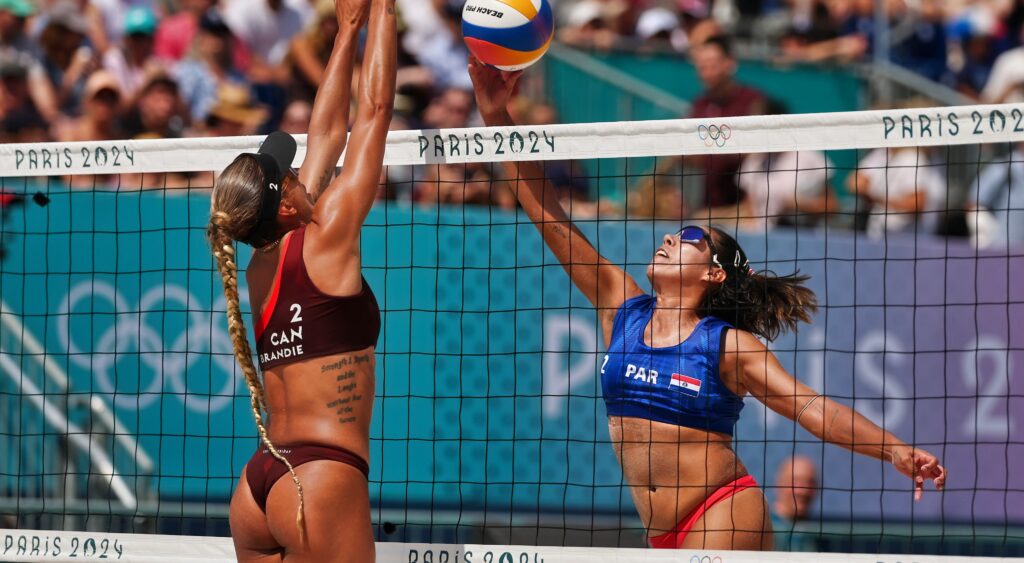 Canada and Paraguay women's beach volleyball players at the net.