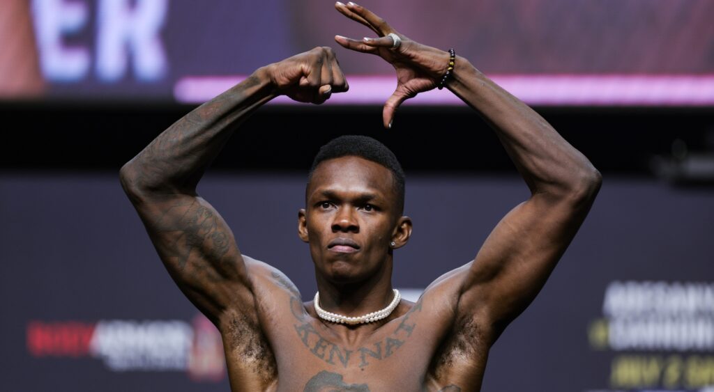 Israel Adesanya poses on the scale 