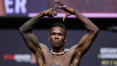 Israel Adesanya poses on the scale