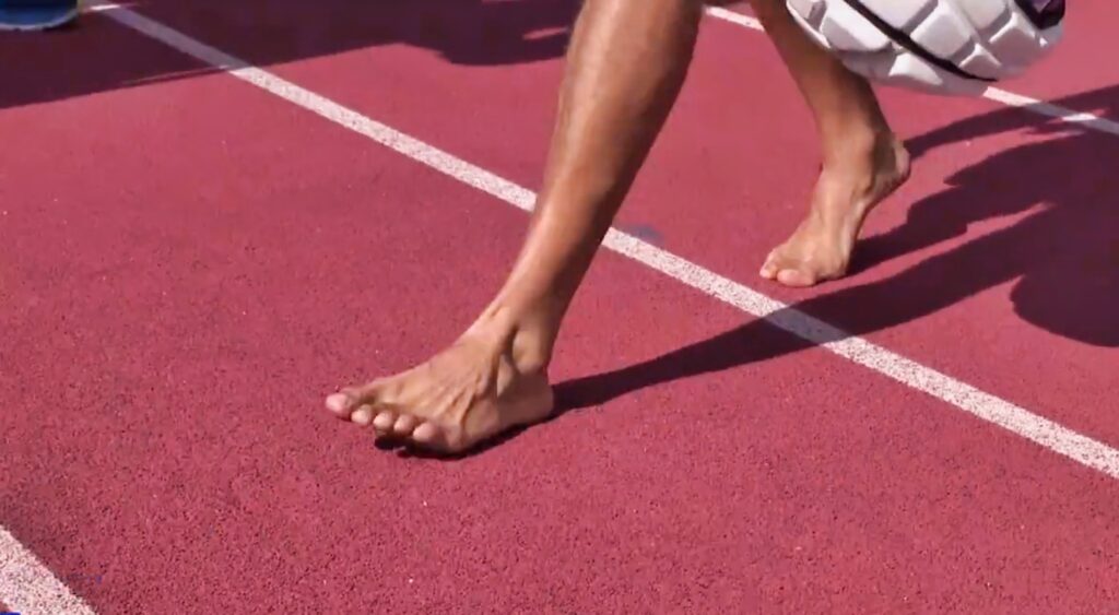 Mack Hollins walks on a track with no shoes.