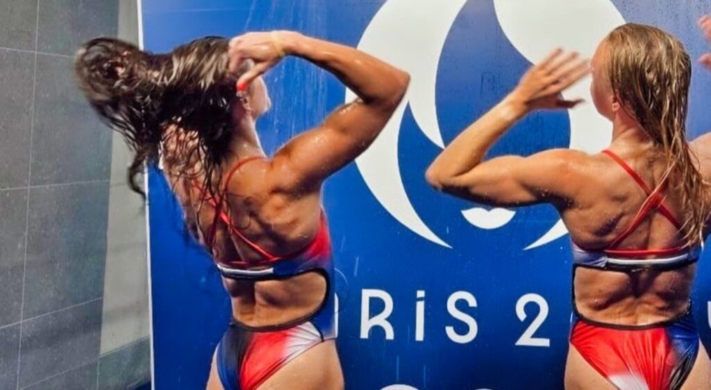 Team USA divers Sarah Bacon and Kassidy Cook taking a shower in their uniforms.