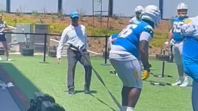 Jim Harbaugh of Los Angeles Chargers pulling offensive lineman with resistance band.