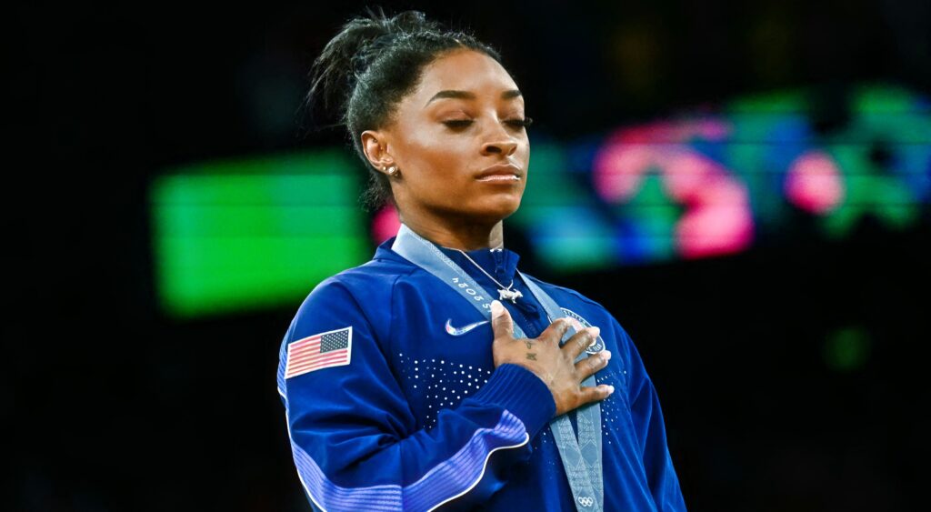 Simone Biles with her hand on her heart