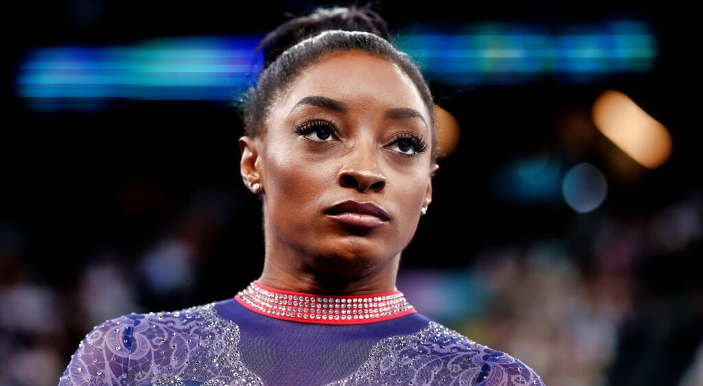 Simone Biles looks on.