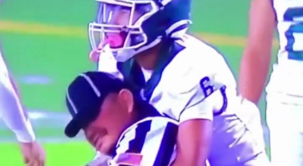 High School Football referee getting tackled by a player.