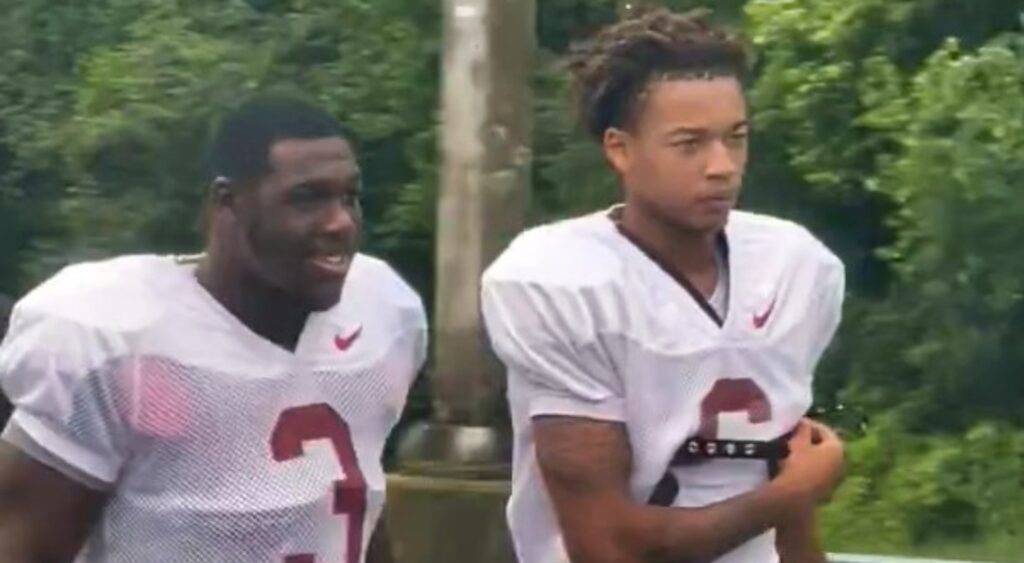 Kam Davis walking with teammate in pads