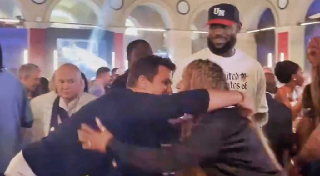 Tom Brady hugs Savannah James as LeBron James looks on.