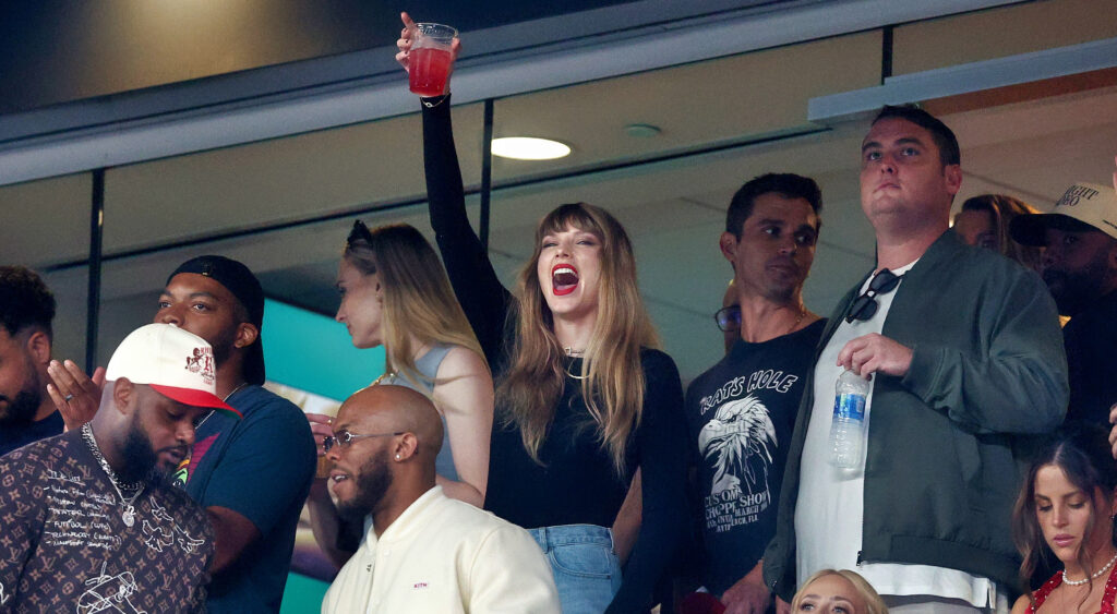 Taylor Swift holding a drink in the air