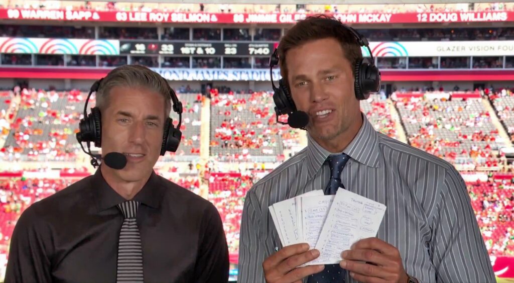 Tom Brady holding up his notes in the broadcast booth.