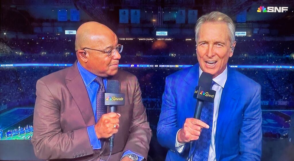 Mike Tirico and Cris Collinsworth speaking in NBC broadcast booth.