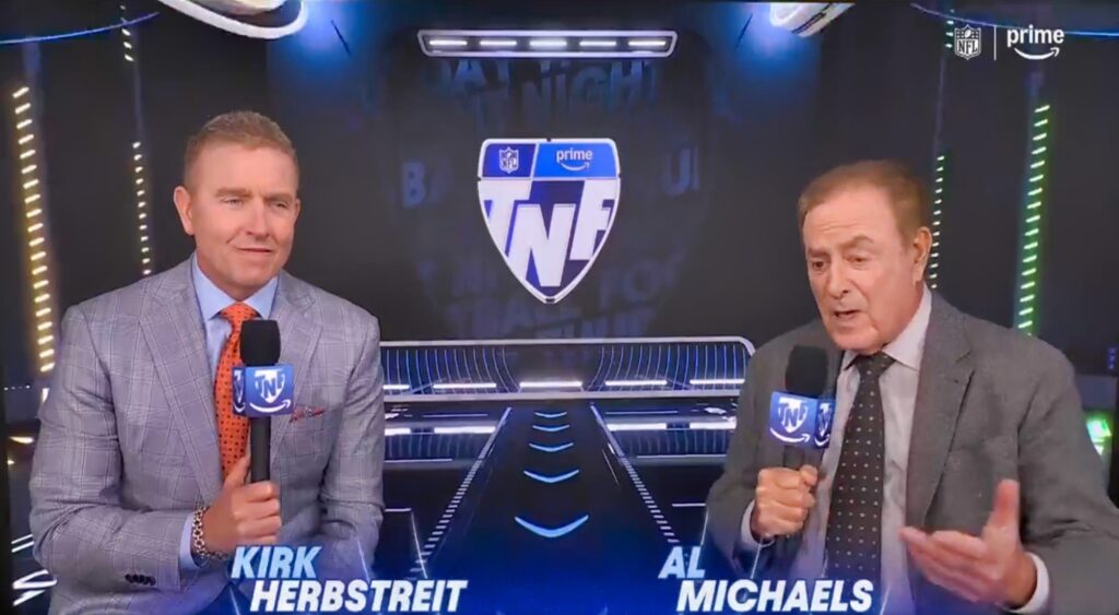 Kirk Herbstreit and Al Michaels talking in broadcast booth.