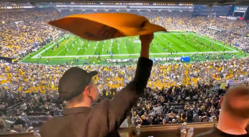 Elon Musk waves his terrible towel at a Steelers game.