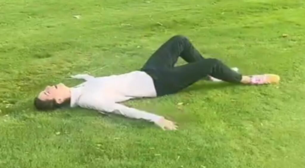 Caitlin Clark lying down on ground after missing a hole-in-one.