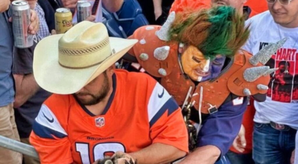 Denver Broncos fan carrying a raccoon.