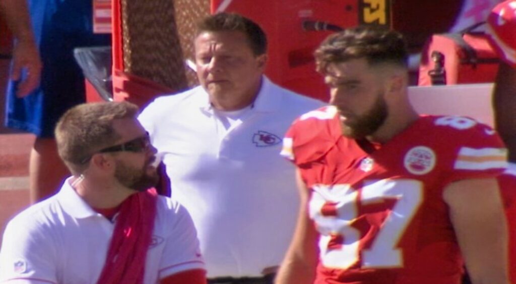 Travis Kelce speaking to Kansas City Chiefs assistant during game.