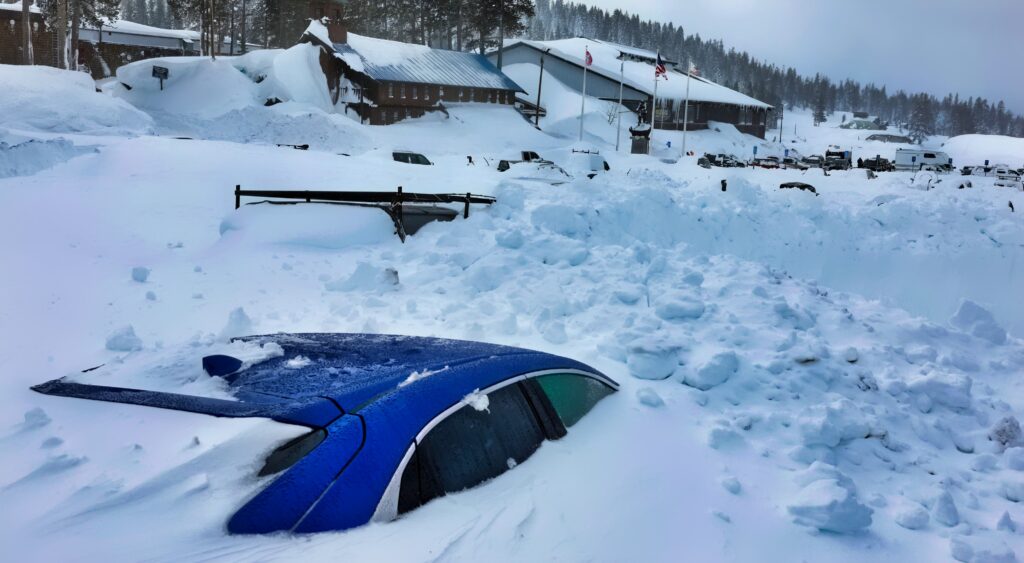 A blizzard buries a car in snow.