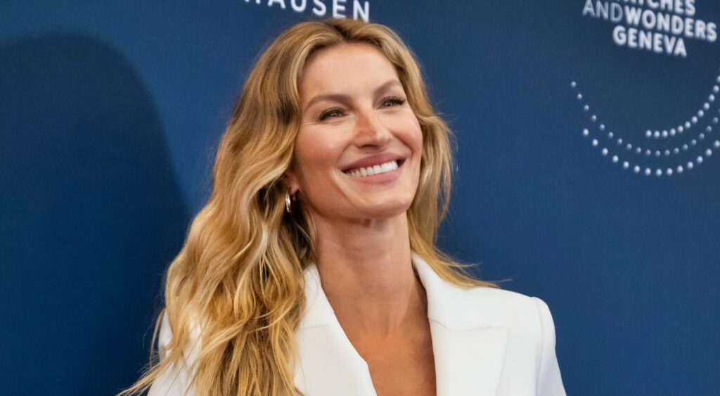 Gisele Bundchen smiling and posing in white outfit